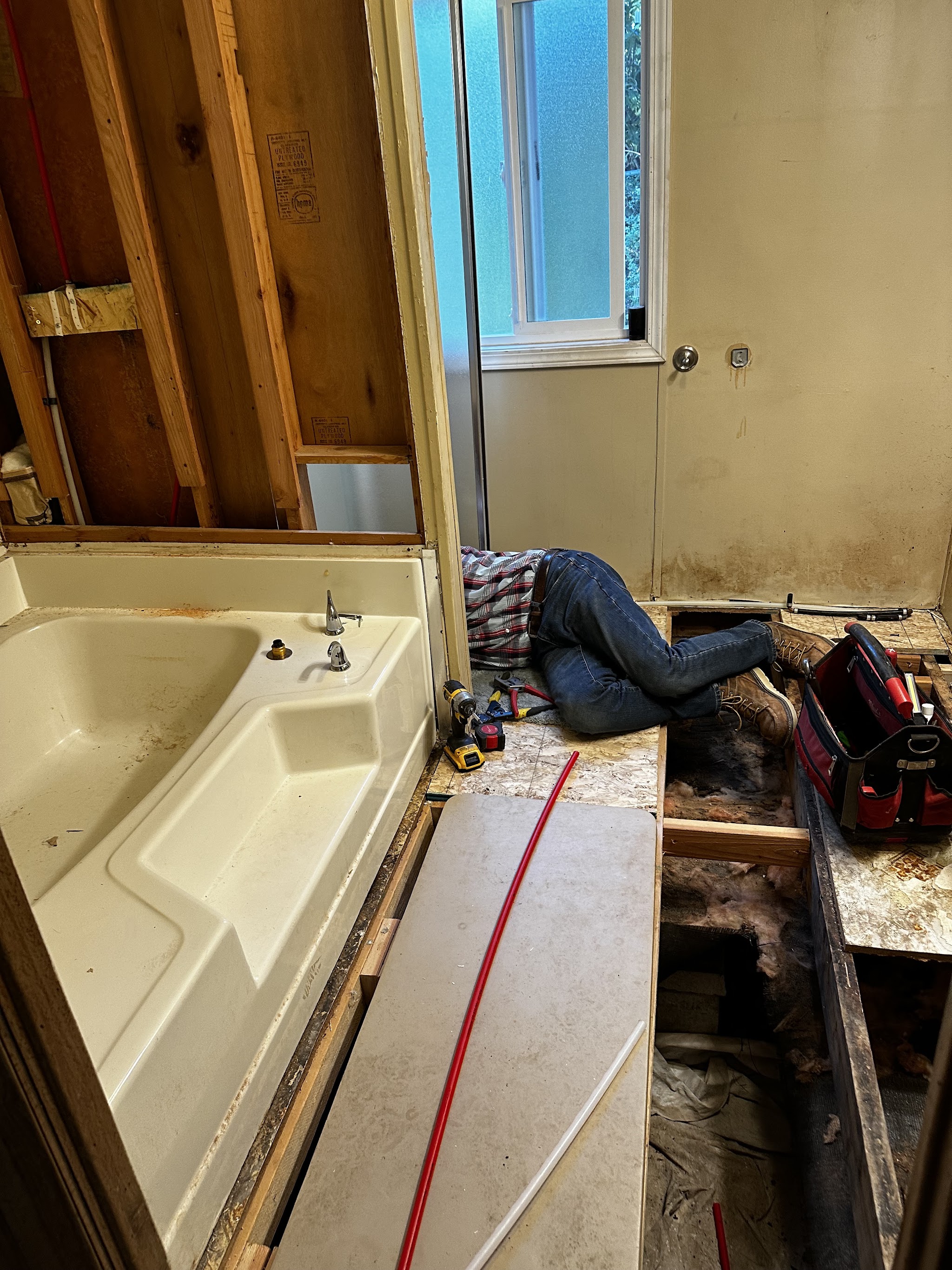 Mike Rokus working underneath an exposed subfloor during a remodel